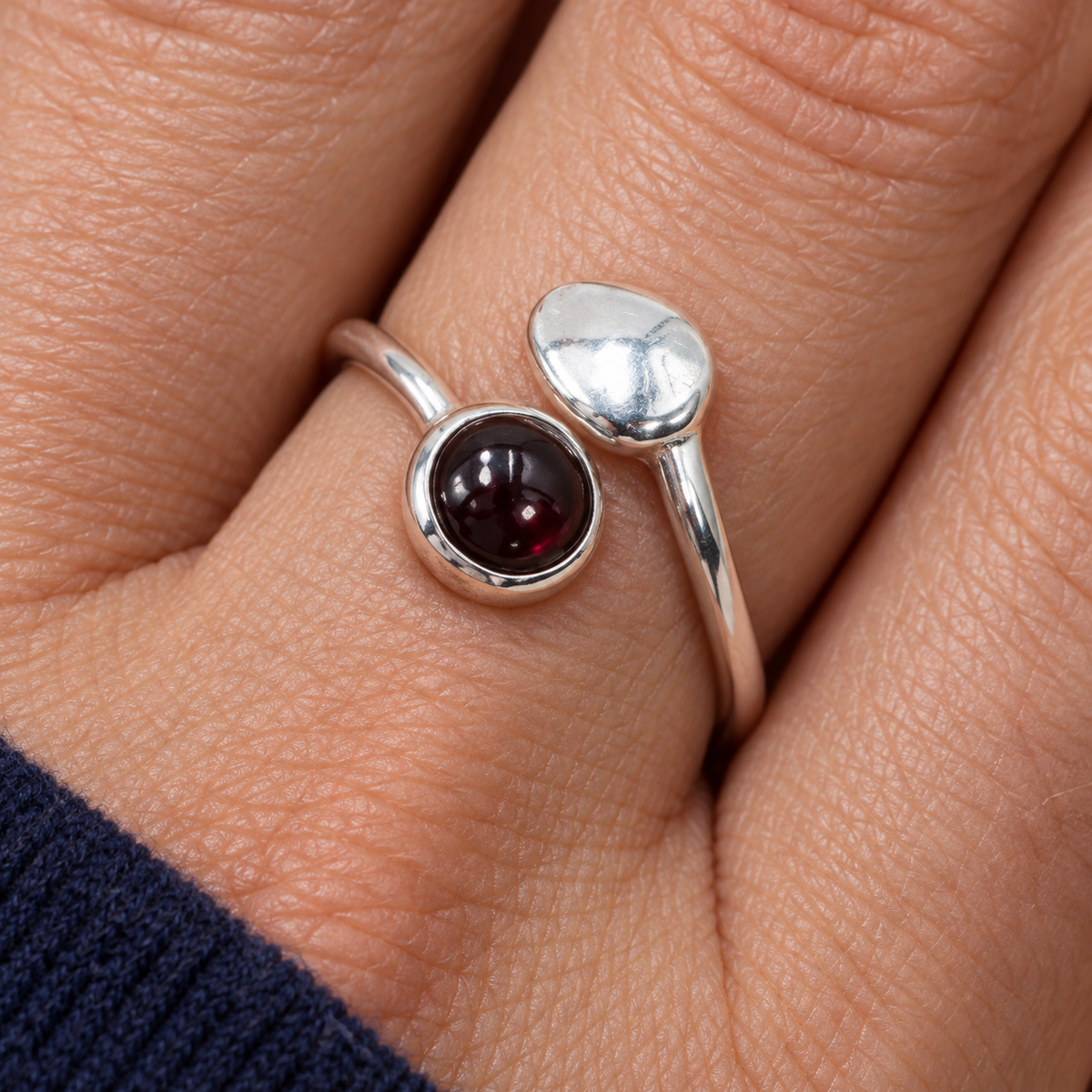 Bague au grenat rhodolite portée au doigt, vue rapprochée du serti et du motif argenté