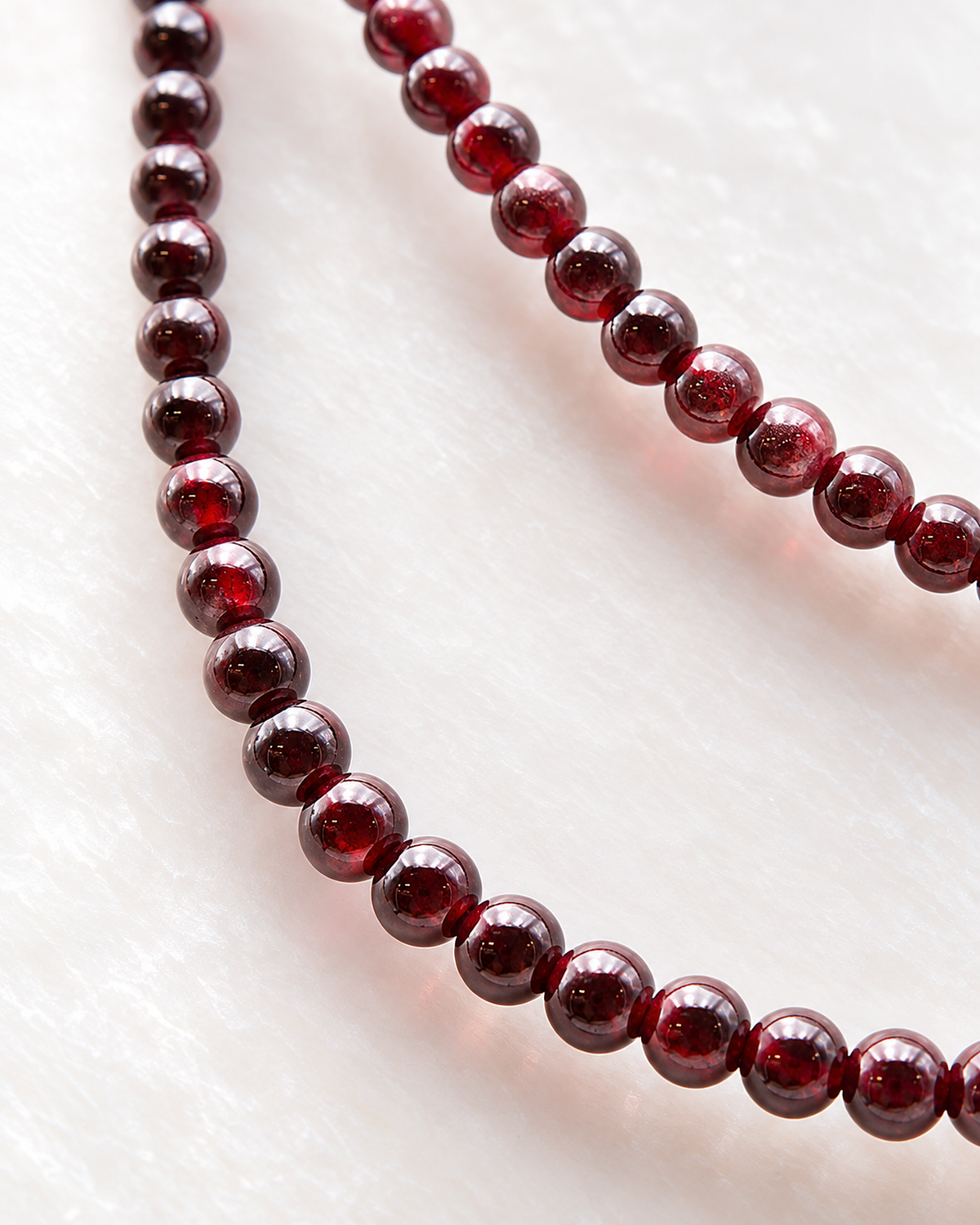 Macro des perles de grenat et de leur finition sur Collier en grenat rouge 4 mm - 45 cm