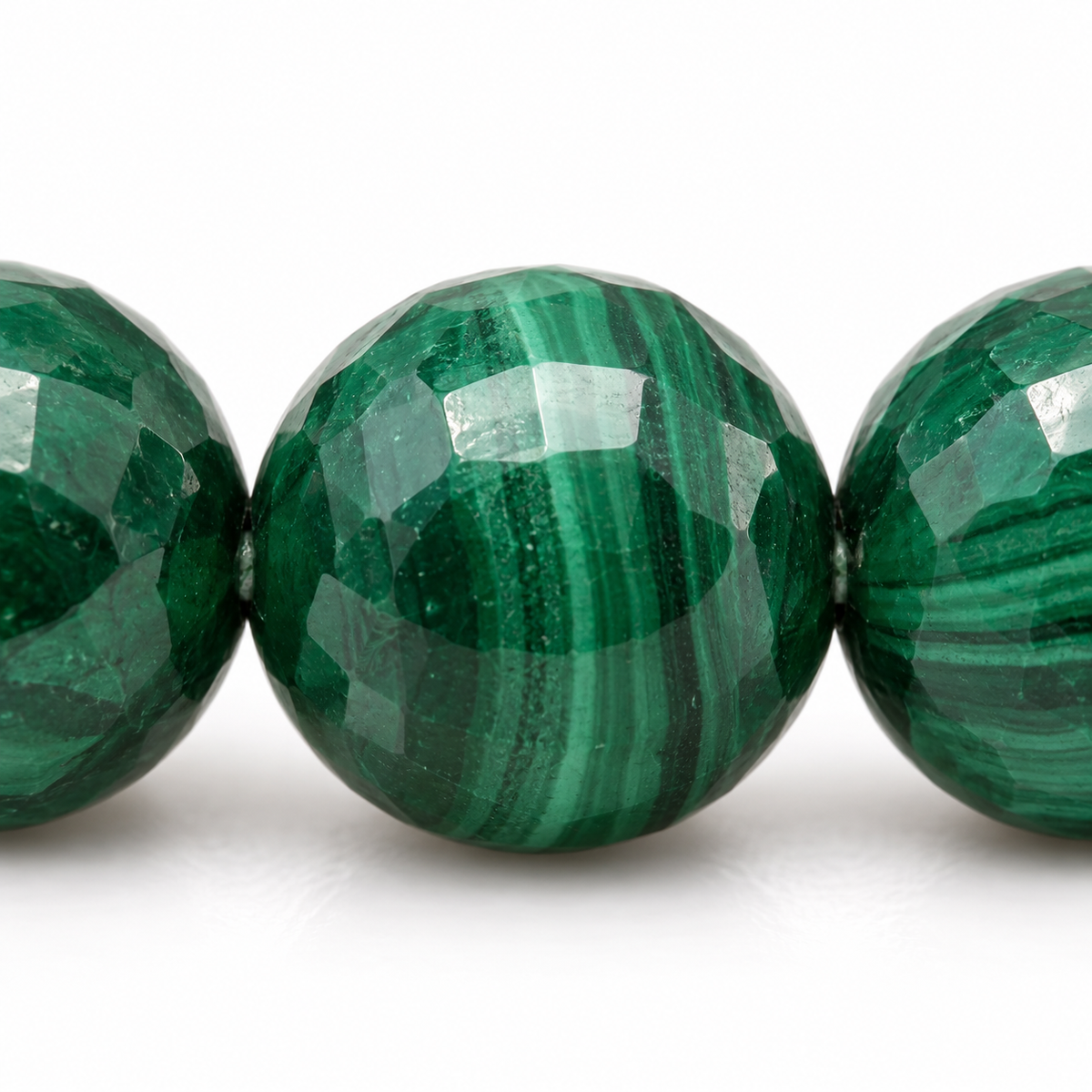 Une perle facettée de malachite et ses voisines dans le bracelet continu