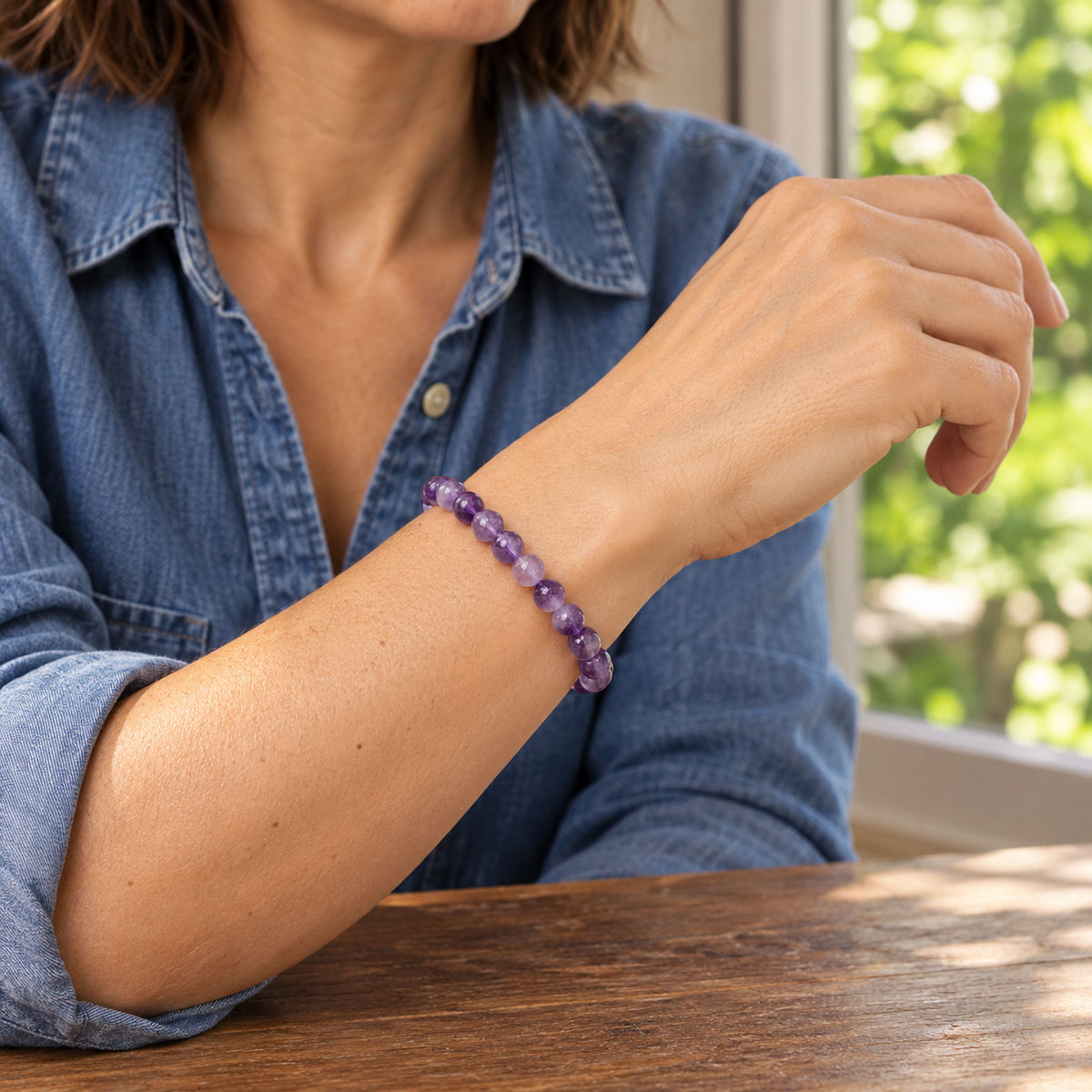 Bracelet en améthyste 6 mm porté près d’une fenêtre donnant sur un jardin.