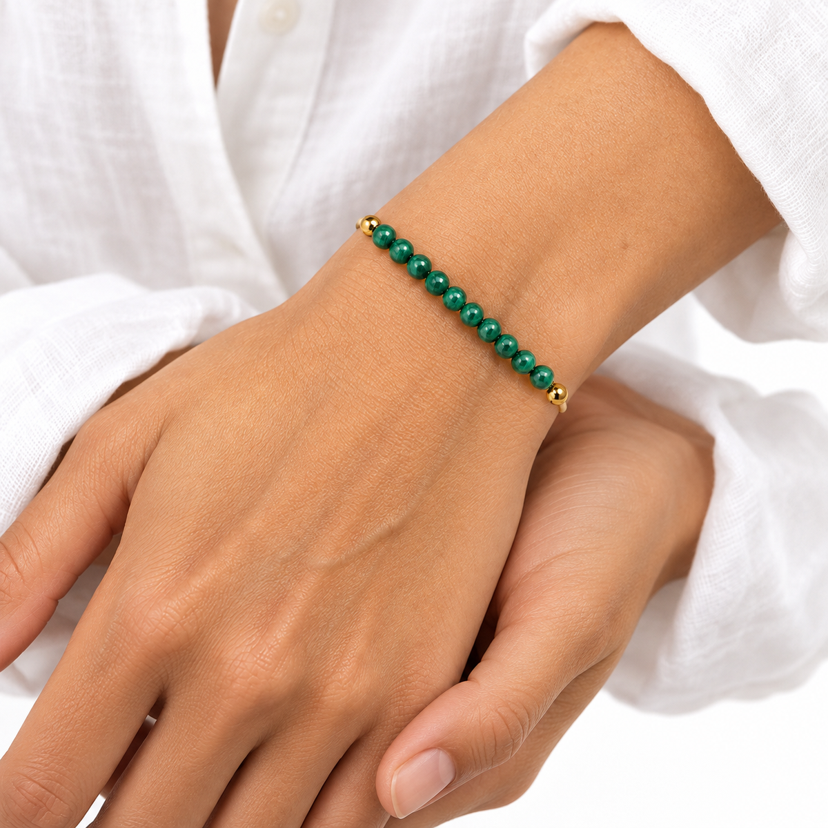 Bracelet malachite porté, main détendue posée sur une surface blanche