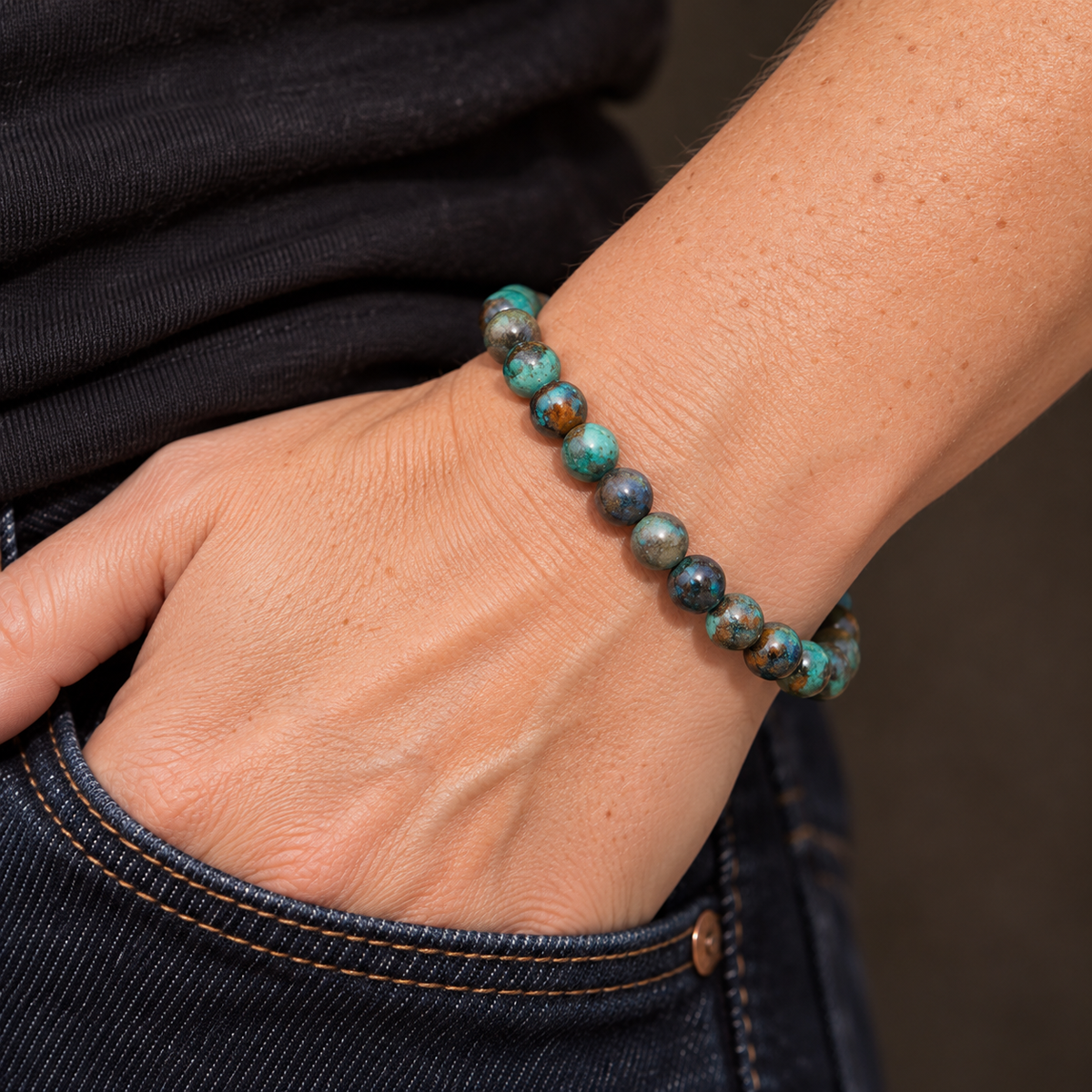 Bracelet en chrysocolle porté de profil au poignet, main près de la poche d’un jean