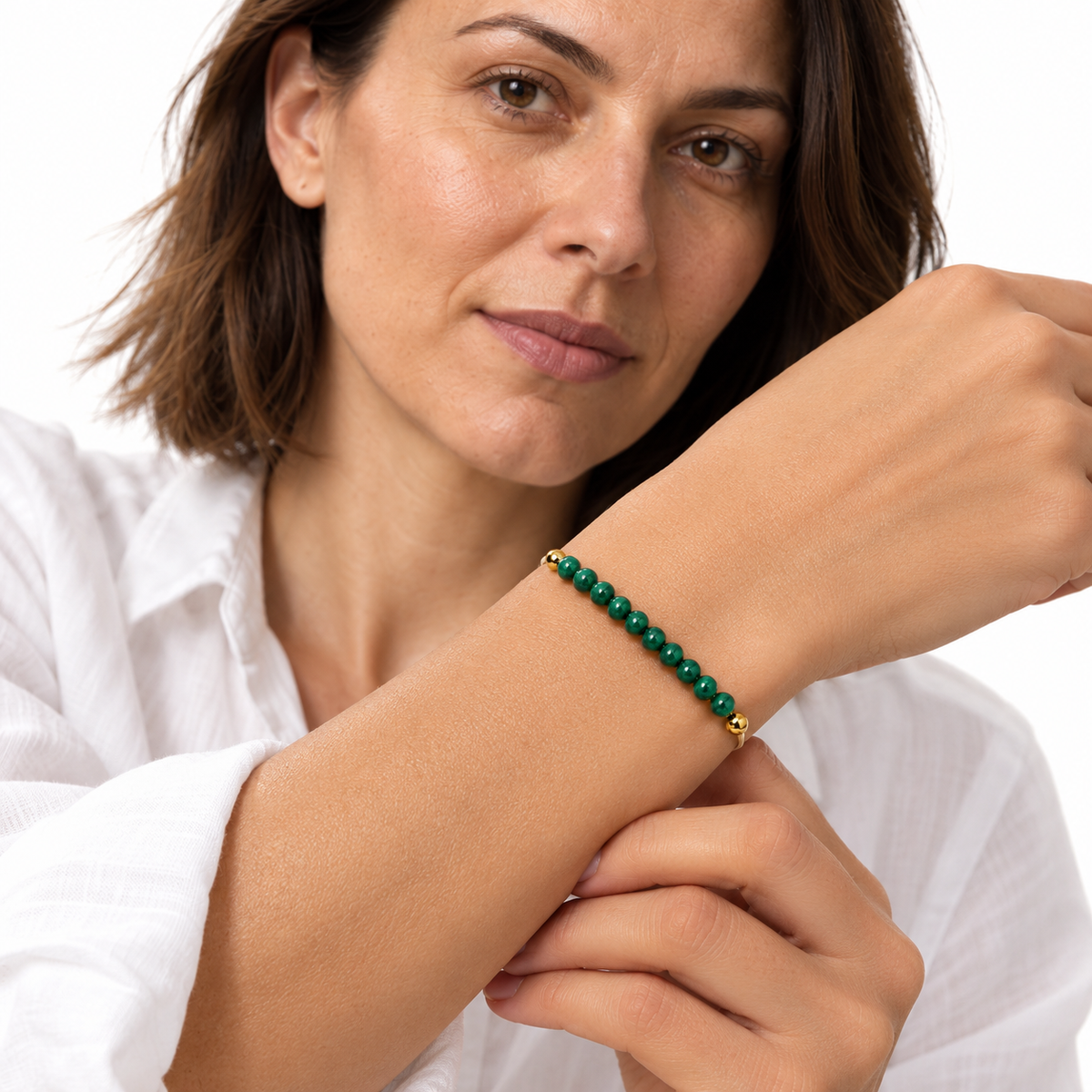 Bracelet malachite porté par Chloé, poignet au premier plan et chemise blanche