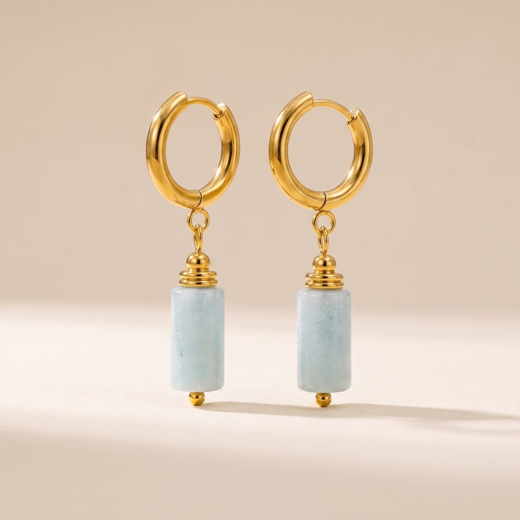 Paire de boucles d'oreilles dorées avec cylindres d'aigue-marine bleu pâle sur fond clair
