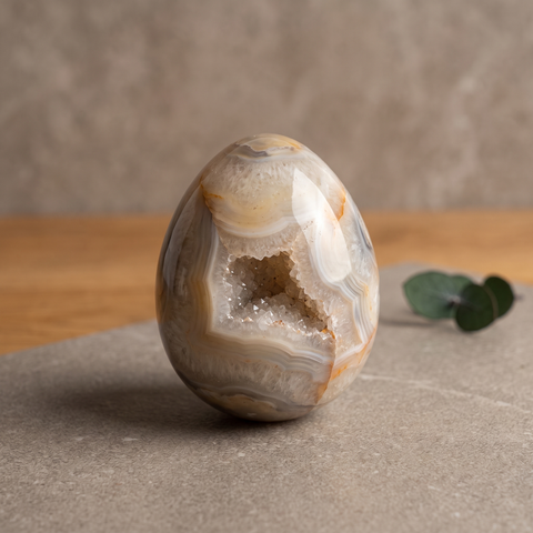 Œuf en agate cristallisée poli avec cavité de petits cristaux sur fond clair