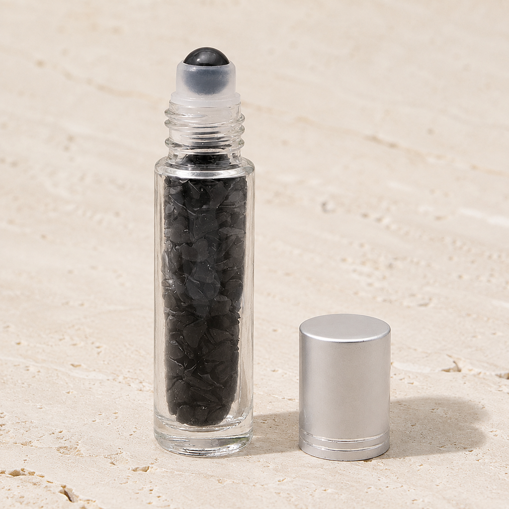 Flacon roll-on en obsidienne noire avec capuchon argenté sur pierre claire