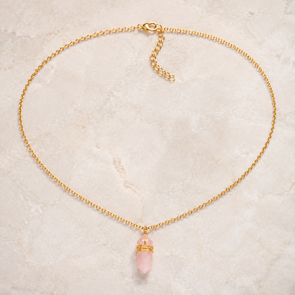 Collier doré en quartz rose présenté en entier sur une surface minérale claire
