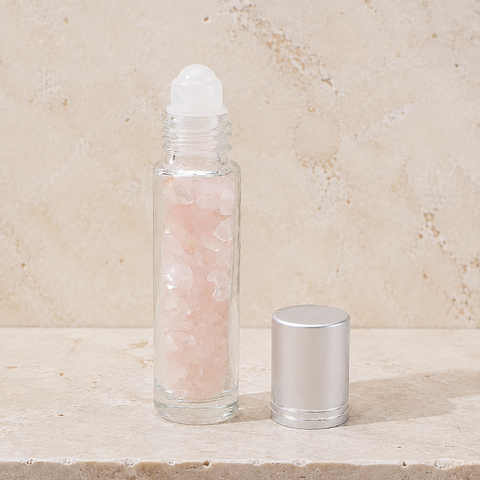 Flacon roll-on en quartz rose avec capuchon argenté sur pierre claire