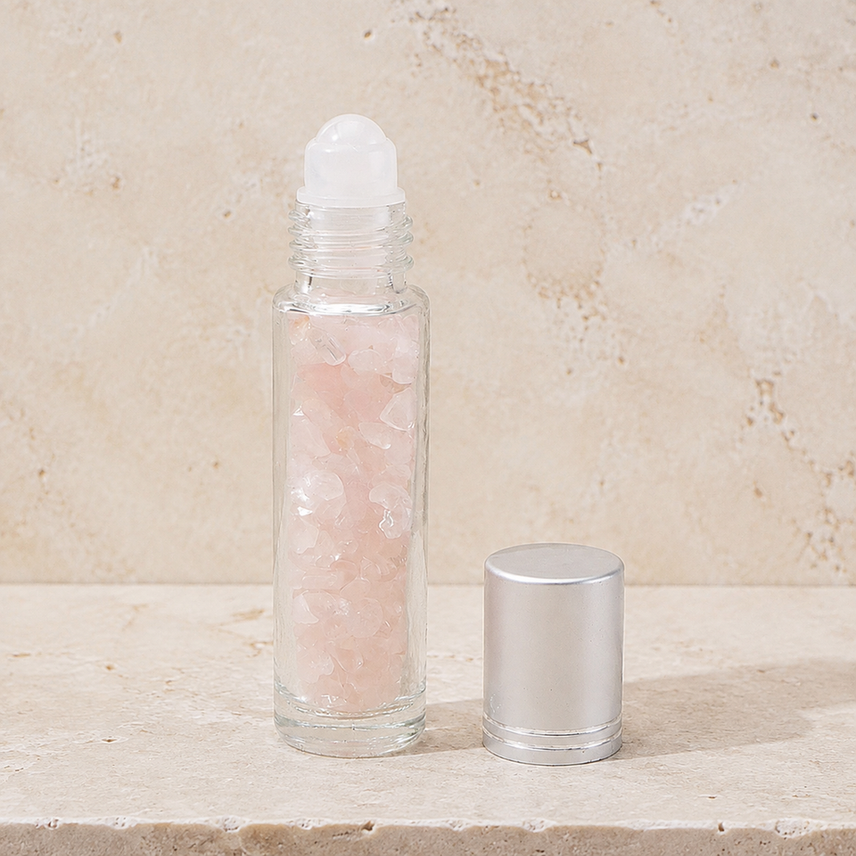 Flacon roll-on en quartz rose avec capuchon argenté sur pierre claire