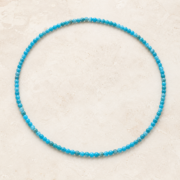 Collier en apatite bleue 4 mm - 45 cm, vue complète sur une surface minérale claire