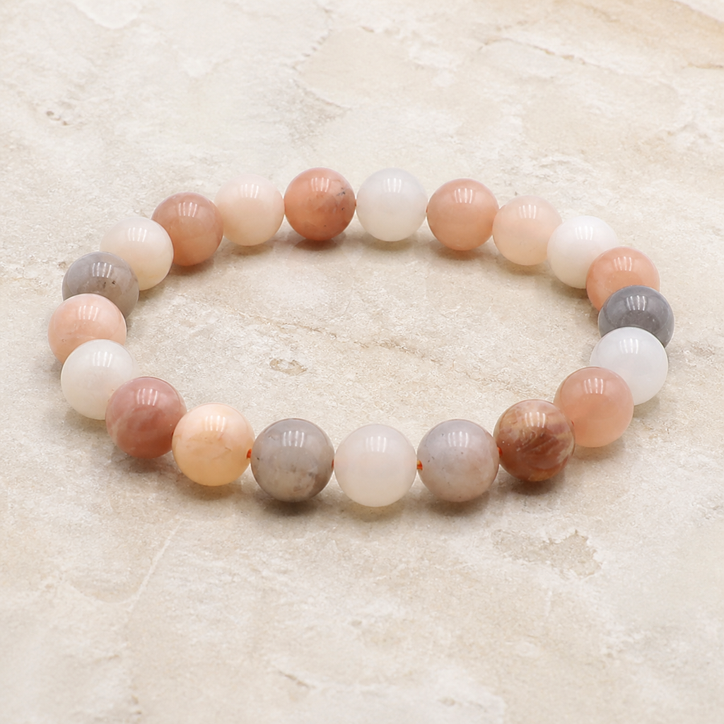 Bracelet en pierre de lune multicolore 10 mm - 16 à 18 cm, vue complète sur une surface minérale claire