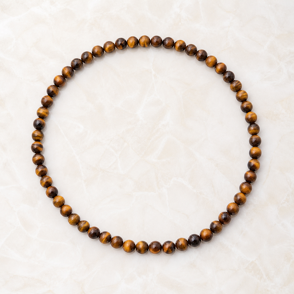 Collier en œil de tigre 6 mm - 45 cm, vue complète sur une surface minérale claire