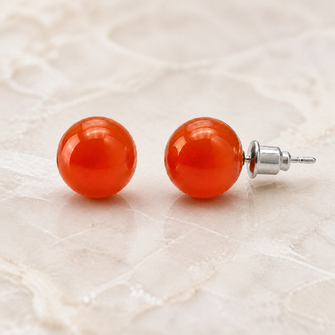 Boucles d'oreilles puces en cornaline - 10 mm, vue complète sur une surface minérale claire