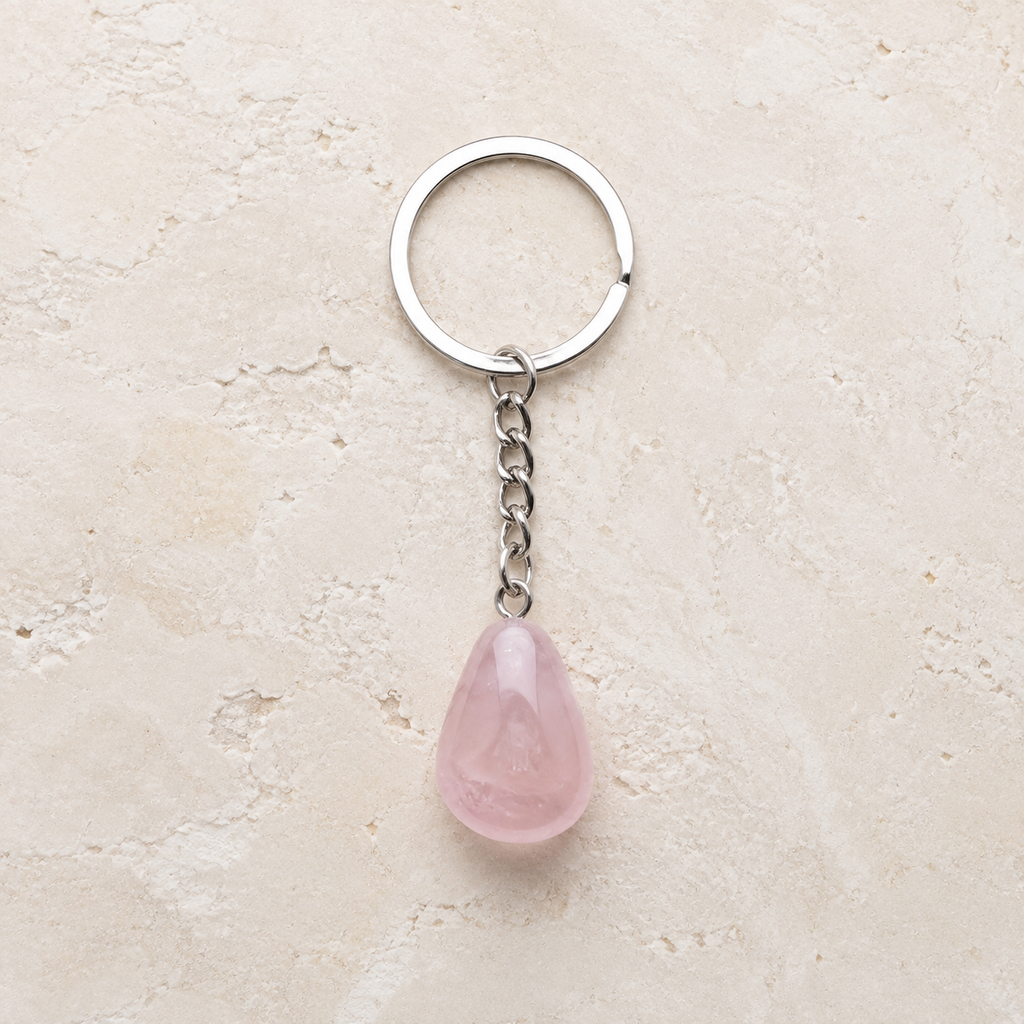 Porte-clés en quartz rose avec anneau argenté sur pierre claire