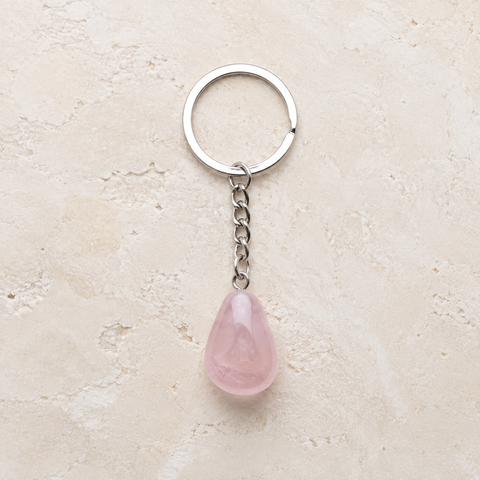 Porte-clés en quartz rose avec anneau argenté sur pierre claire