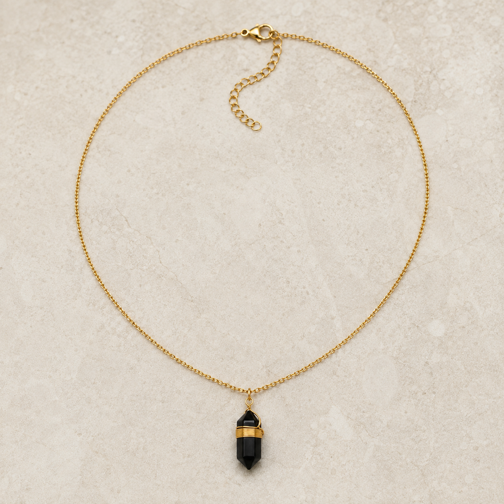 Collier doré en obsidienne noire présenté en entier sur une surface minérale claire
