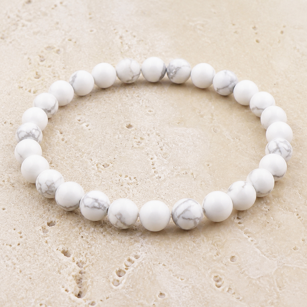 Bracelet en howlite blanche - Perles de 6 mm, vue complète sur une surface minérale claire