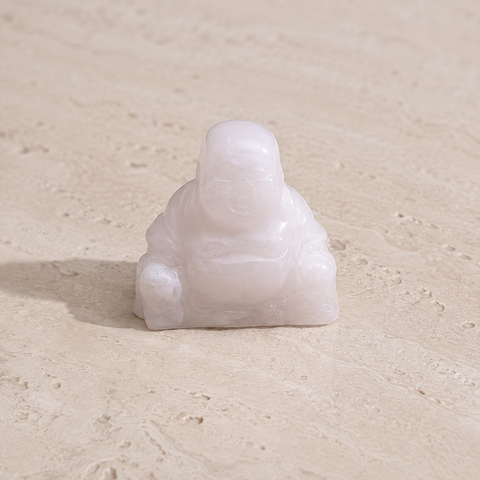 Petit Bouddha souriant en cristal de roche laiteux sur pierre claire