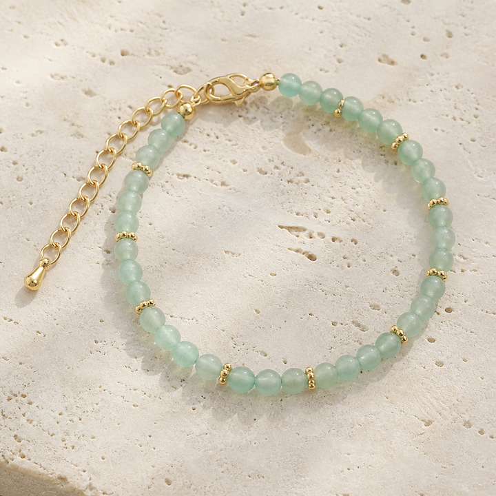Bracelet Halo doré en aventurine verte 4 mm, vue complète sur une surface minérale claire