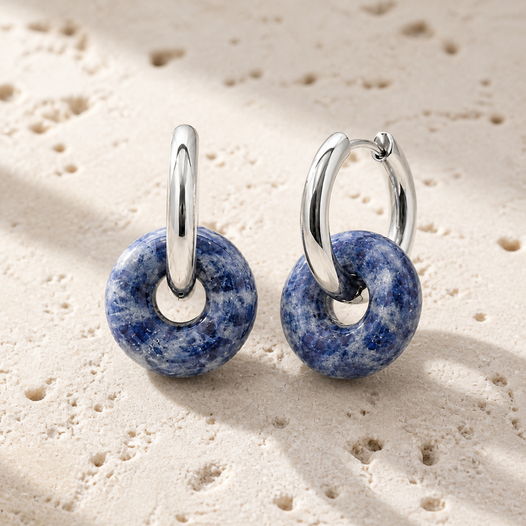 Boucles d'oreilles Loa argentées en sodalite 25 mm, vue complète sur une surface minérale claire