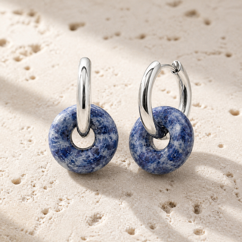 Boucles d'oreilles Loa argentées en sodalite 25 mm, vue complète sur une surface minérale claire