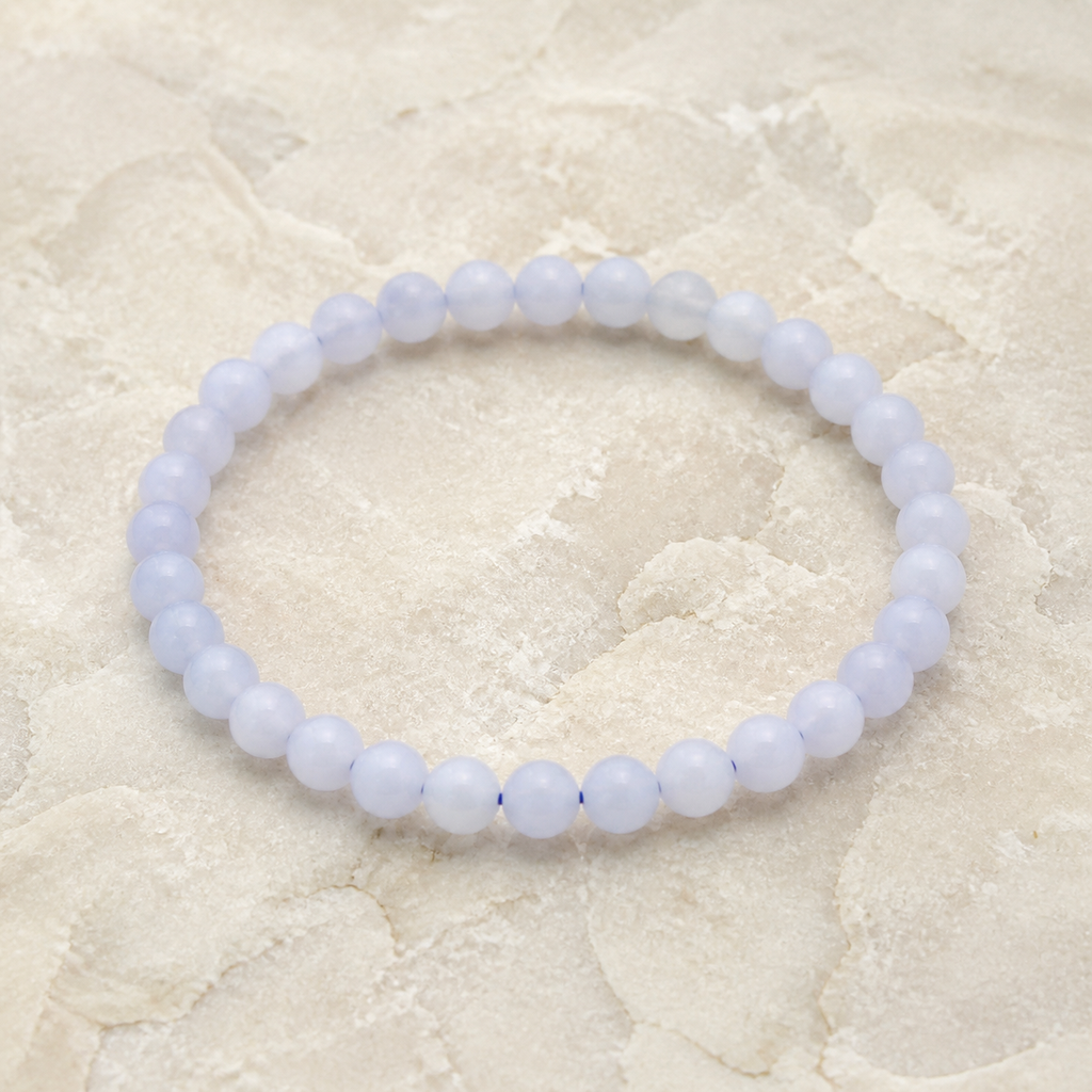 Bracelet en calcédoine bleue de Namibie - Perles de 6 mm, vue complète sur une surface minérale claire