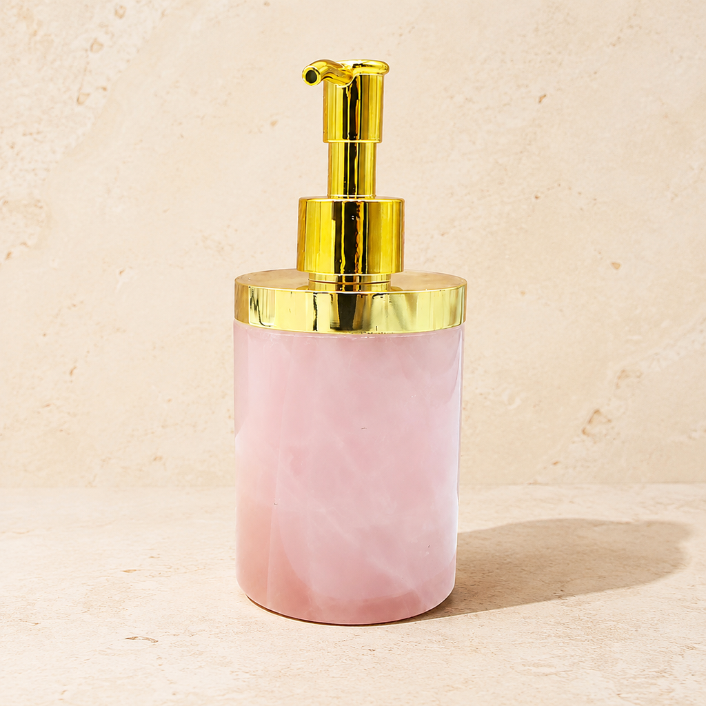 Distributeur en quartz rose laiteux avec pompe dorée sur pierre claire