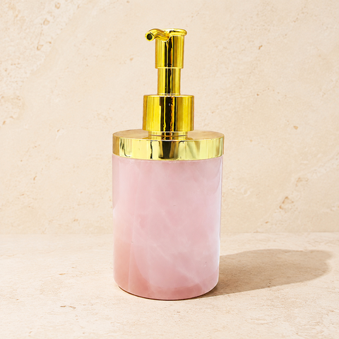Distributeur en quartz rose laiteux avec pompe dorée sur pierre claire