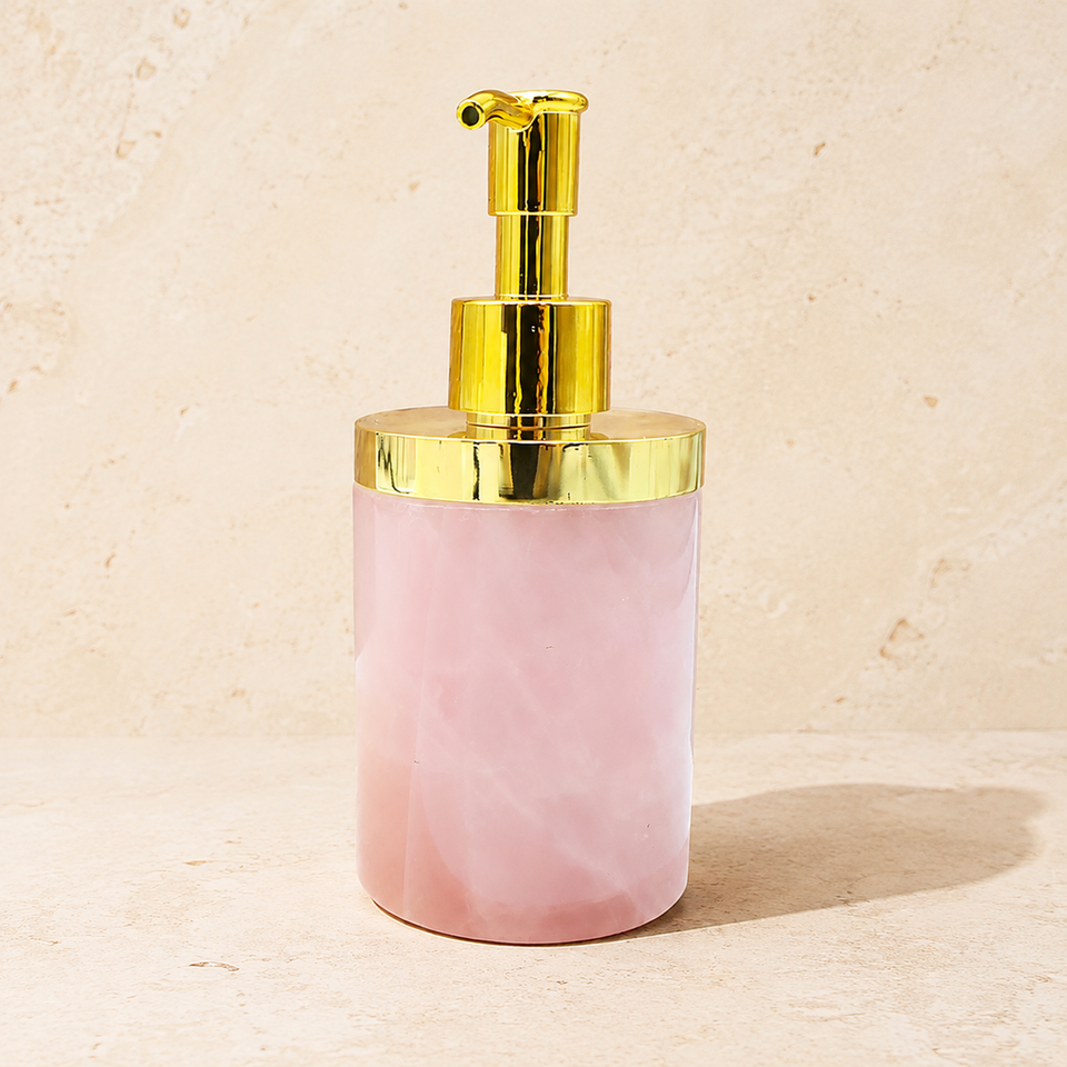 Distributeur en quartz rose laiteux avec pompe dorée sur pierre claire