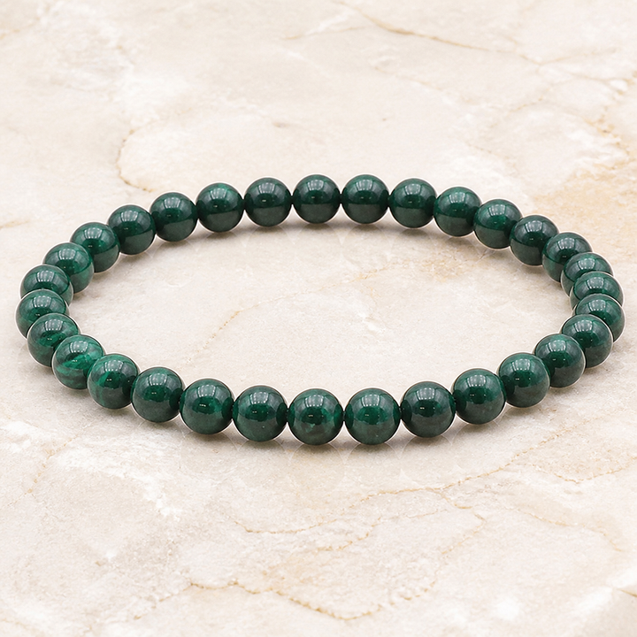 Bracelet en malachite - Perles de 6 mm, vue complète sur une surface minérale claire