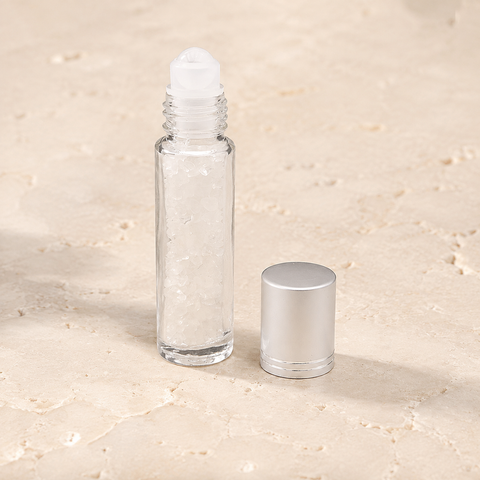 Flacon roll-on en cristal de roche avec capuchon argenté sur pierre claire