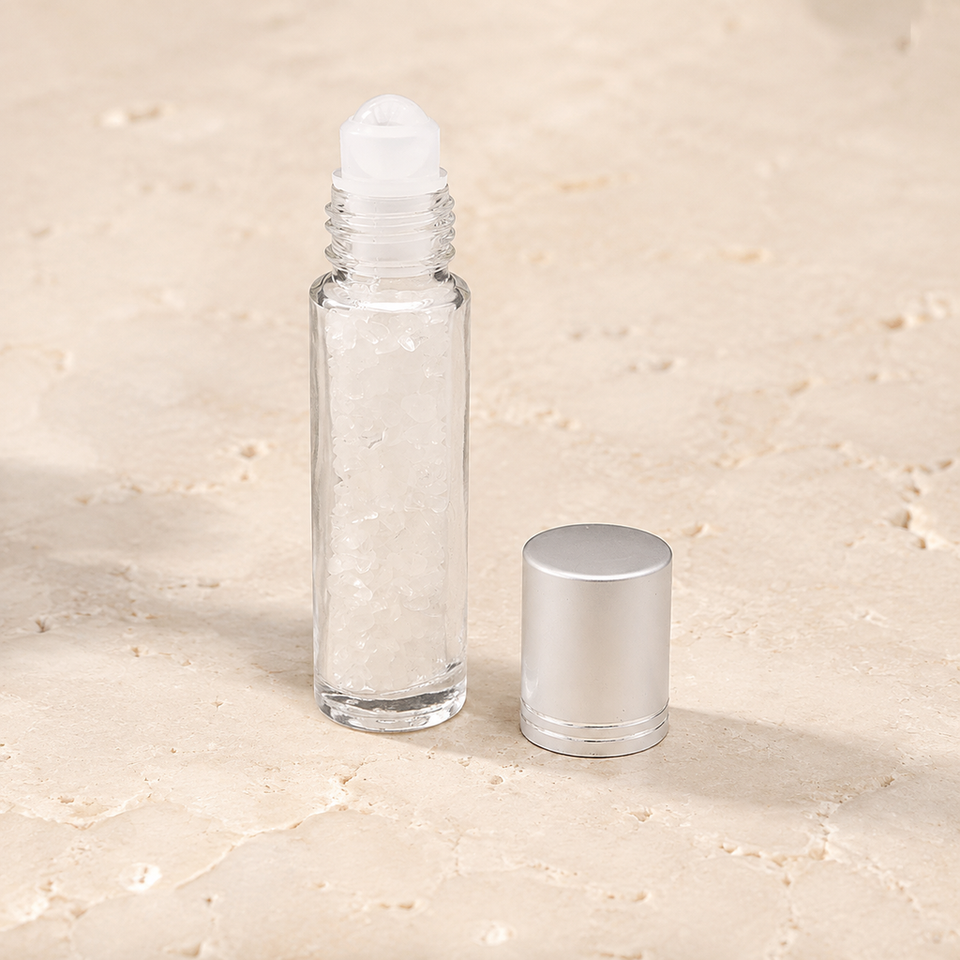 Flacon roll-on en cristal de roche avec capuchon argenté sur pierre claire