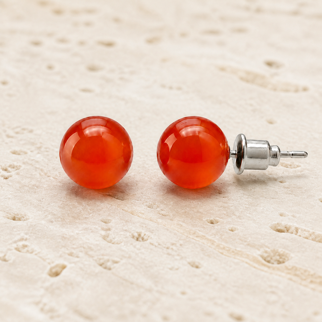 Boucles d'oreilles puces en cornaline 8 mm, vue complète sur une surface minérale claire