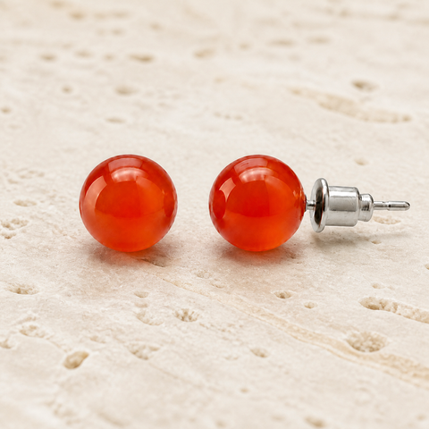 Boucles d'oreilles puces en cornaline 8 mm, vue complète sur une surface minérale claire