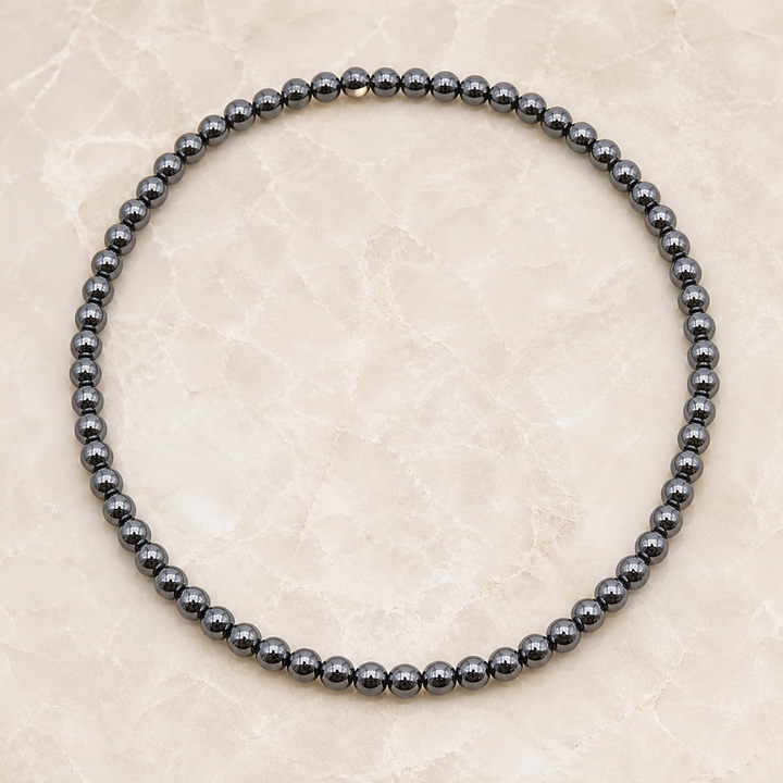 Collier en hématite 6 mm - 45 cm, vue complète sur une surface minérale claire