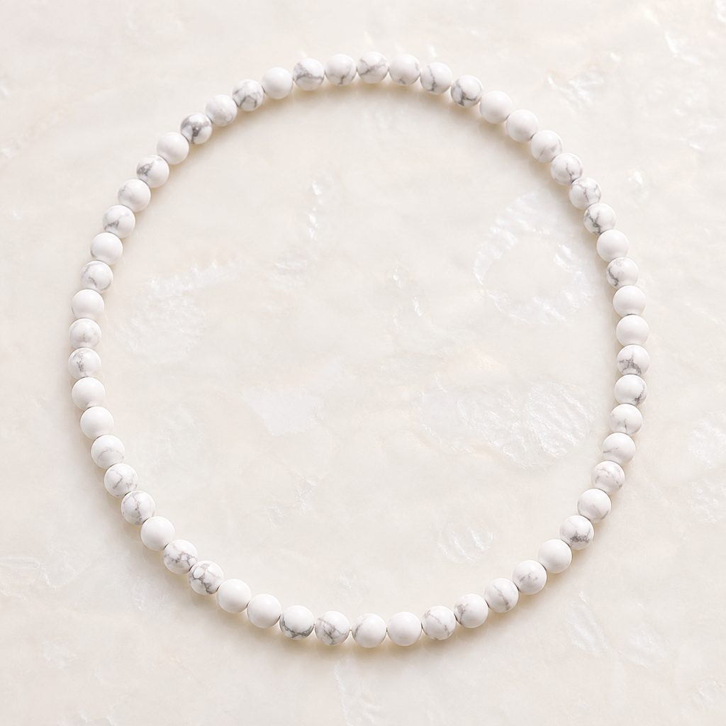Collier en howlite blanche 6 mm - 45 cm, vue complète sur une surface minérale claire