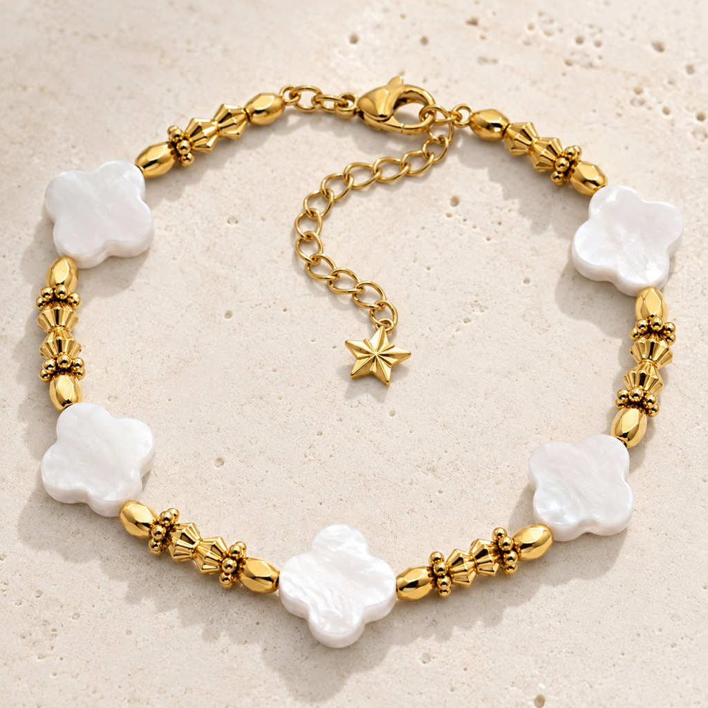 Bracelet doré à fleurs de nacre présenté en entier sur une surface minérale claire