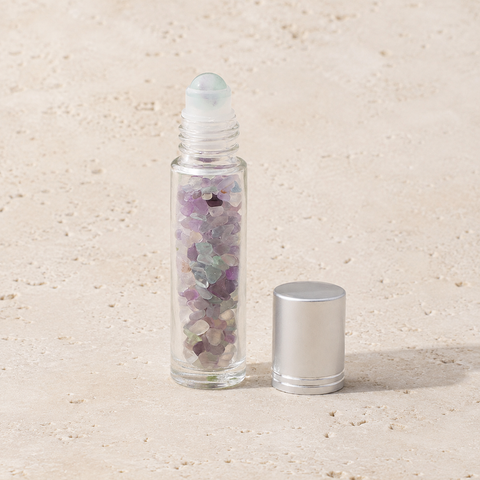 Flacon roll-on en fluorine multicolore avec capuchon argenté sur pierre claire