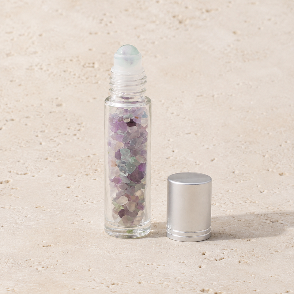 Flacon roll-on en fluorine multicolore avec capuchon argenté sur pierre claire