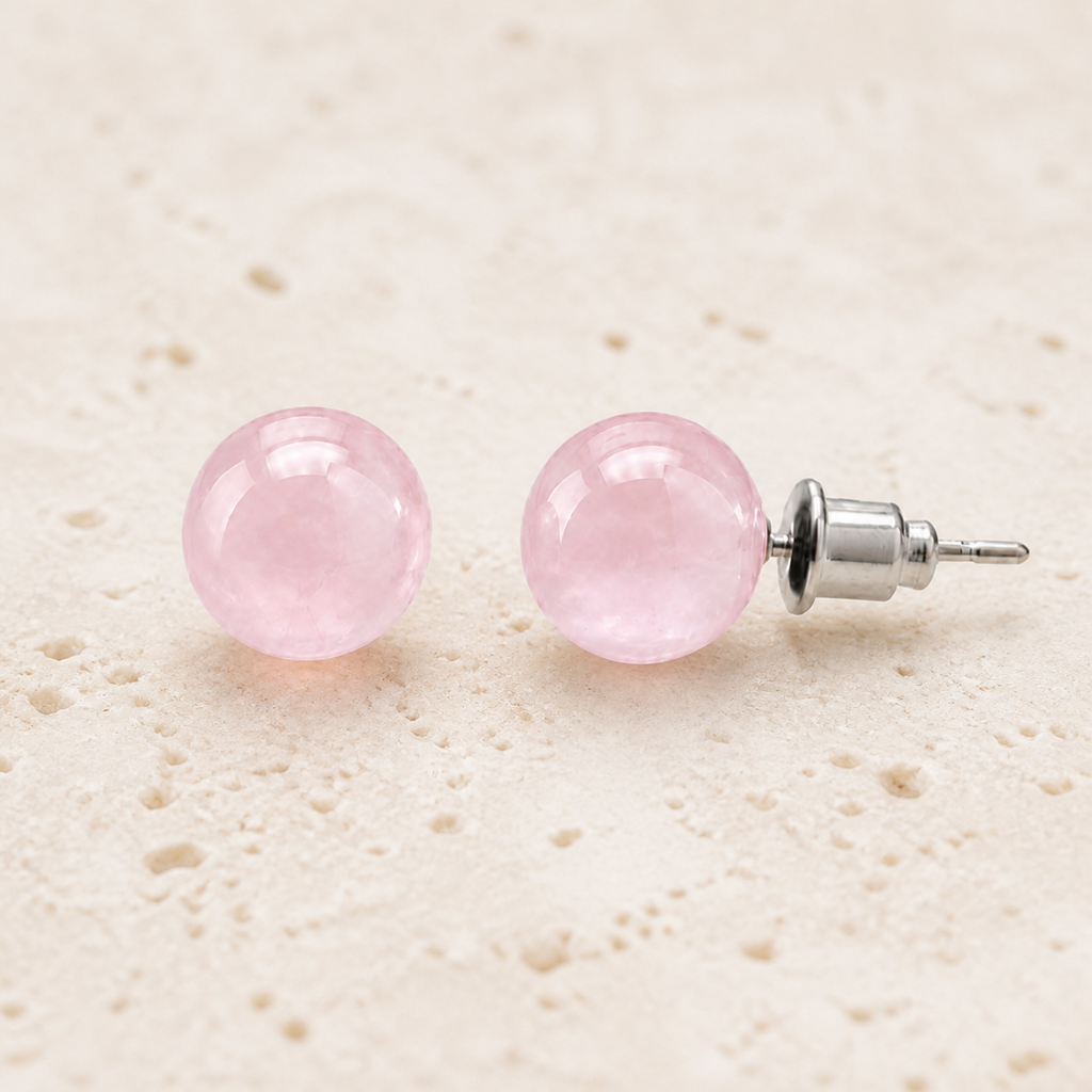 Boucles d'oreilles puces en quartz rose 8 mm, vue complète sur une surface minérale claire
