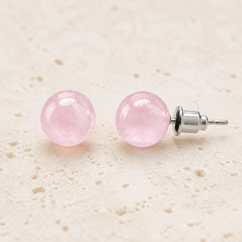 Boucles d'oreilles puces en quartz rose 8 mm, vue complète sur une surface minérale claire