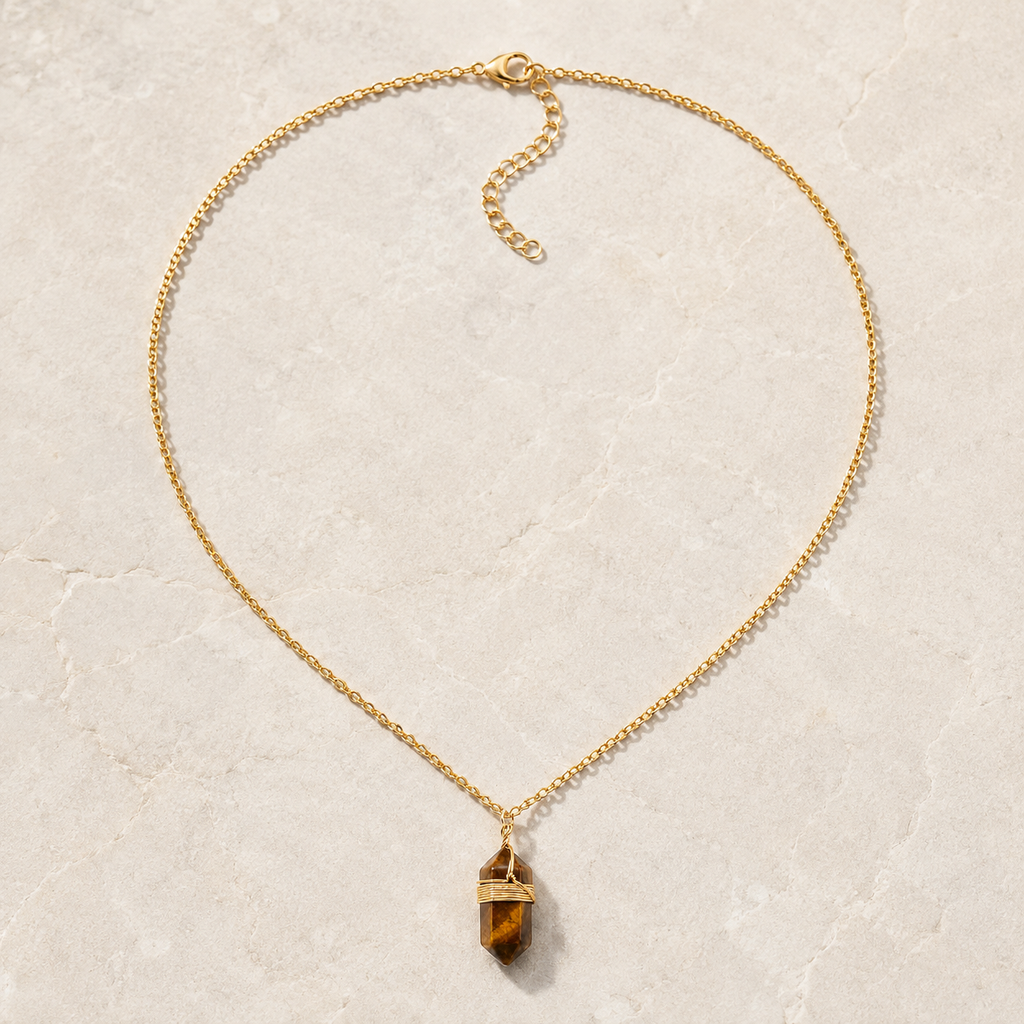 Collier doré en œil de tigre présenté en entier sur une surface minérale claire