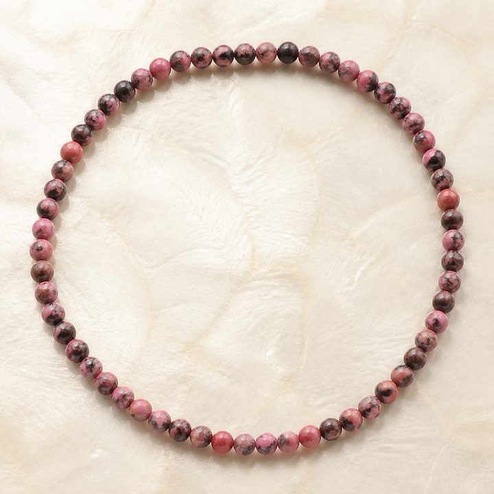 Collier en rhodonite de Madagascar 6 mm - 45 cm, vue complète sur une surface minérale claire