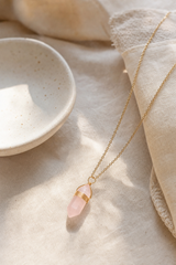 Collier quartz rose doré présenté dans une ambiance douce et naturelle