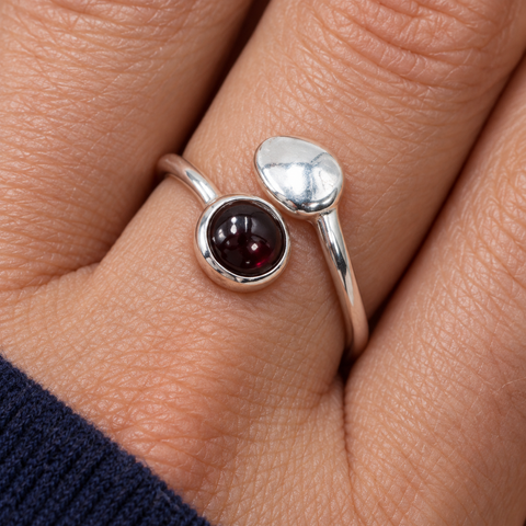 Bague au grenat rhodolite portée au doigt, vue rapprochée du serti et du motif argenté