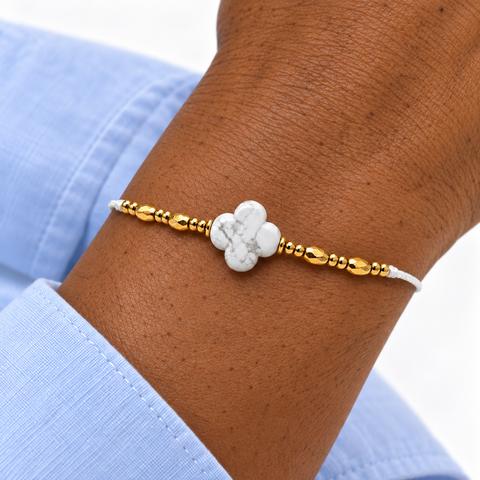 Bracelet fleur de howlite blanche porté au poignet, détails dorés et manche bleu clair