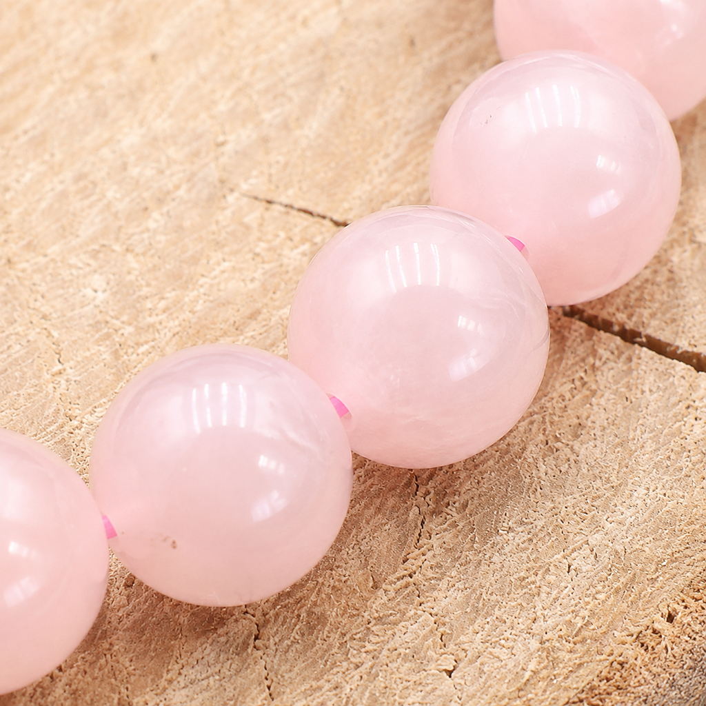 Gros plan sur les perles rondes et le rose laiteux du bracelet en quartz rose