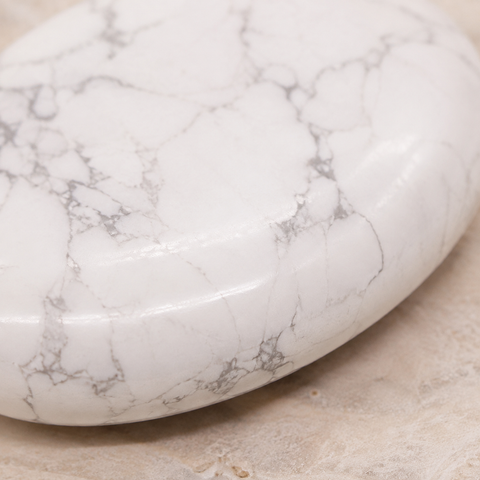 Gros plan de la surface polie et des veines du galet en howlite blanche