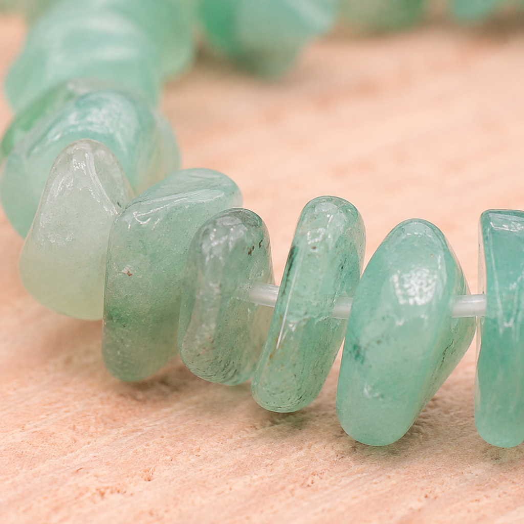 Macro des éclats polis de aventurine verte et de leur fil élastique