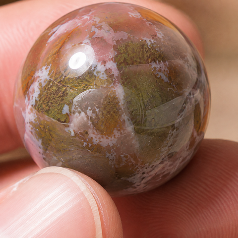 Macro des dessins de la sphère en agate indienne entre les doigts